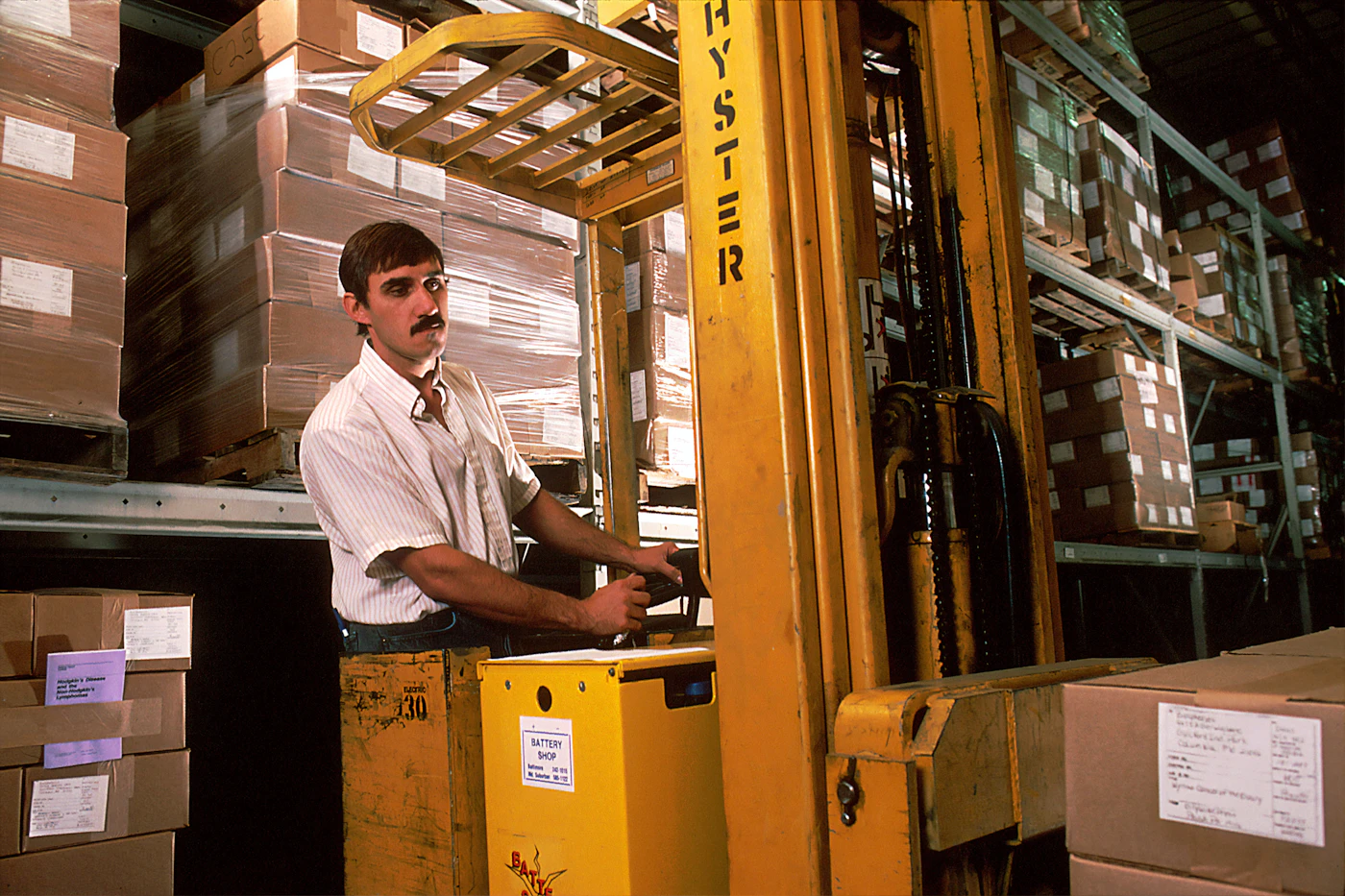 Forklift operator moving boxes between warehouse racks